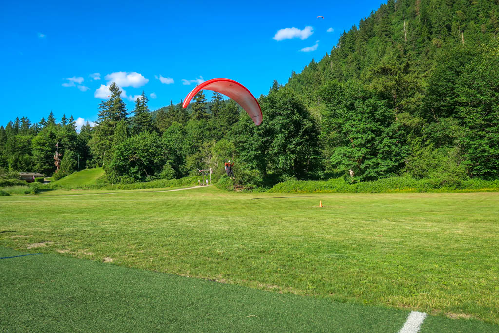 A paraglider lands on the field next to Poo Poo Point Chirico Trail