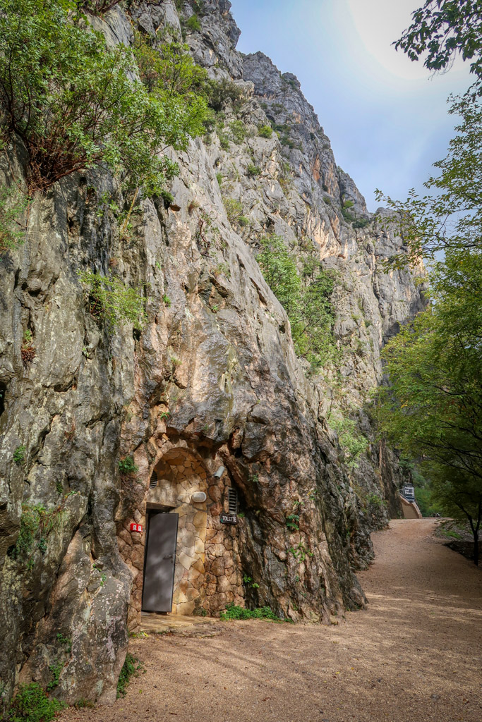 A door leads into the bottom of a limestone canyon wall along the trail
