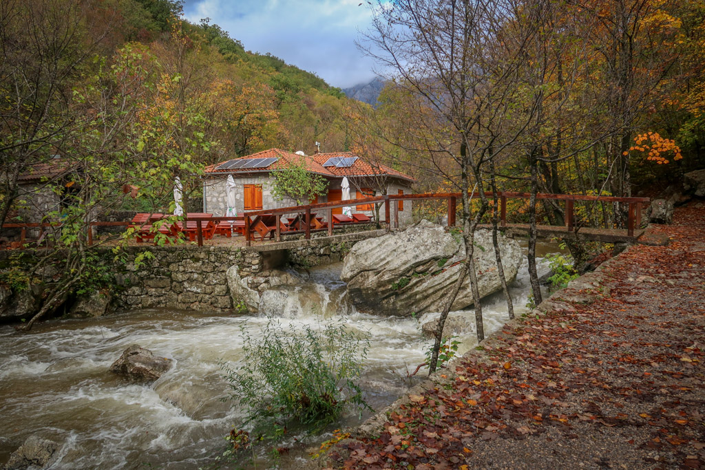 An idyllic hut is perched on a ledge on the other side of the river reached by an arched bridge