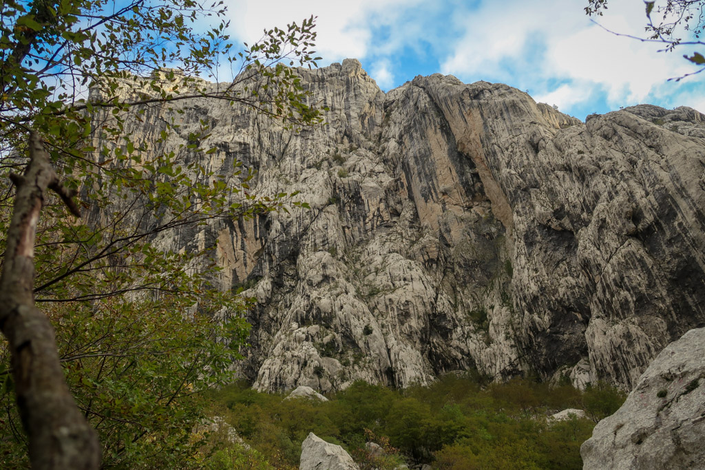 A tall craggy limestone wall streaked with black and yellow