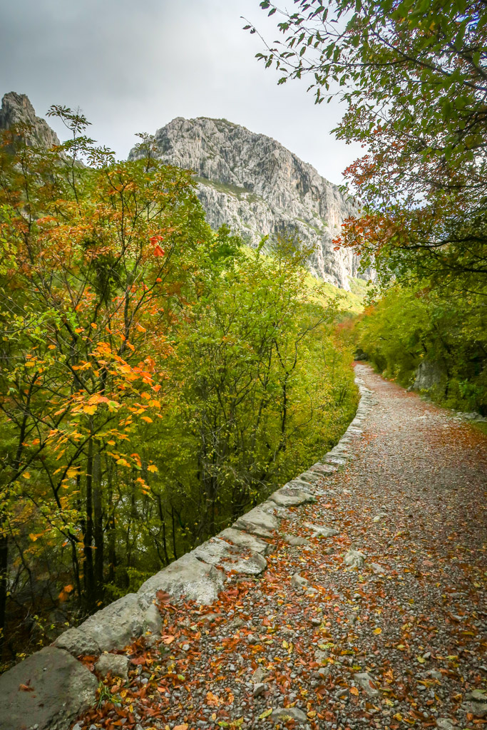A hiking trail with the tall limestone cliff of Anića kuk looming in the distance