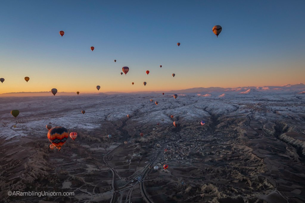 Cappadocia balloon ride with snow covered mountains in the distance.