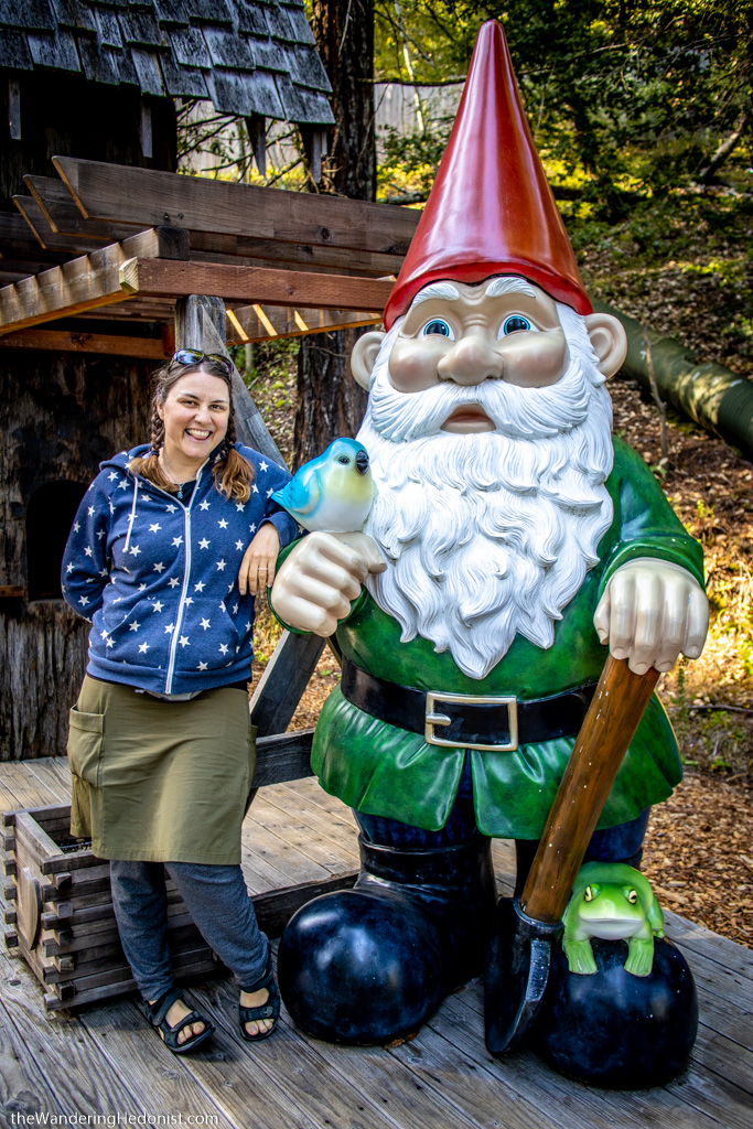 Photo of the author standing next to a life-sized gnome with a red pointy hat.