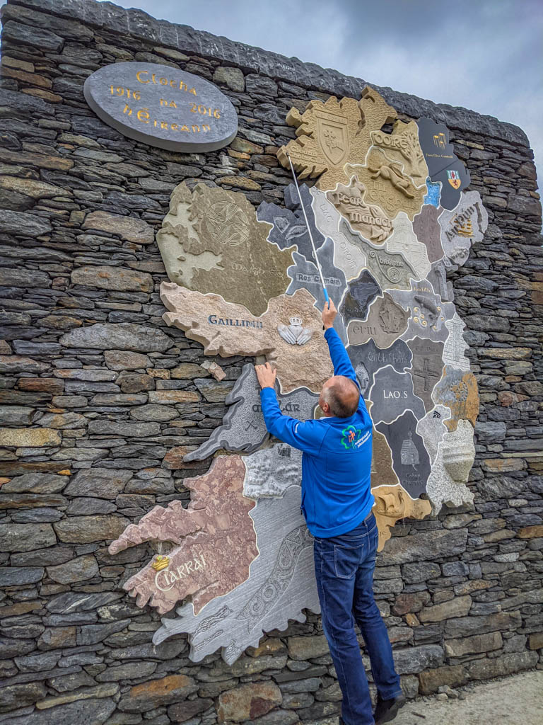 John stands on his tip toes and uses a long pointer to indicate our location in Donegal County on a large stone map of Ireland