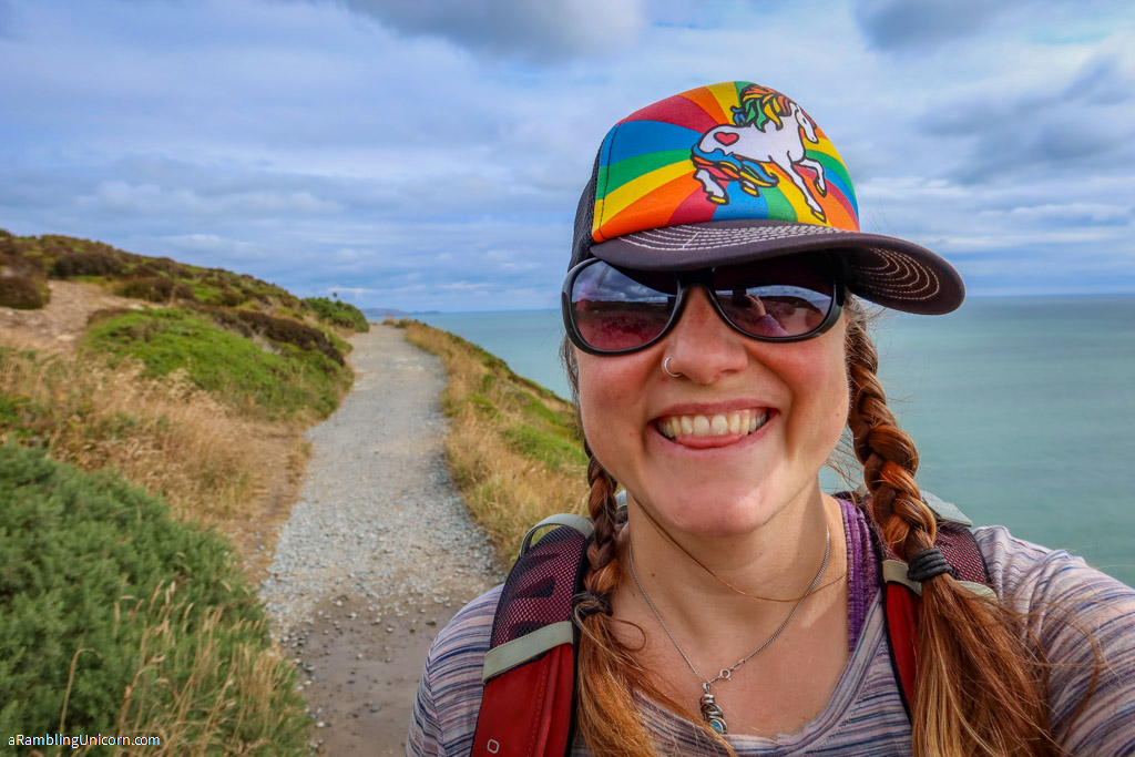 Selfie of the author in a rainbow unicorn hat on the Howth Cliff Walk
