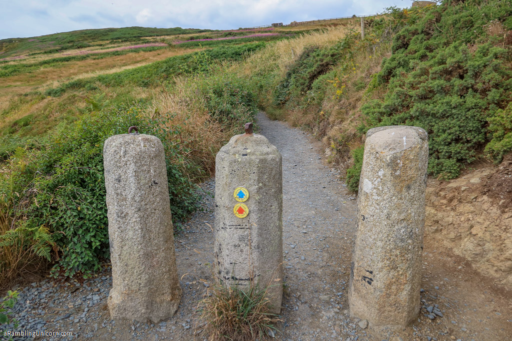 Three concrete barriers prevent cyclists from accessing the Cliff Walk Trail. The barriers have markers to indicate the cliff walk paths. 