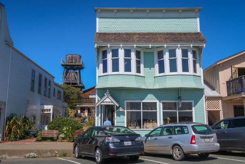 A historic building along Mendocino's Main Street with a wooden water tower in the backgound