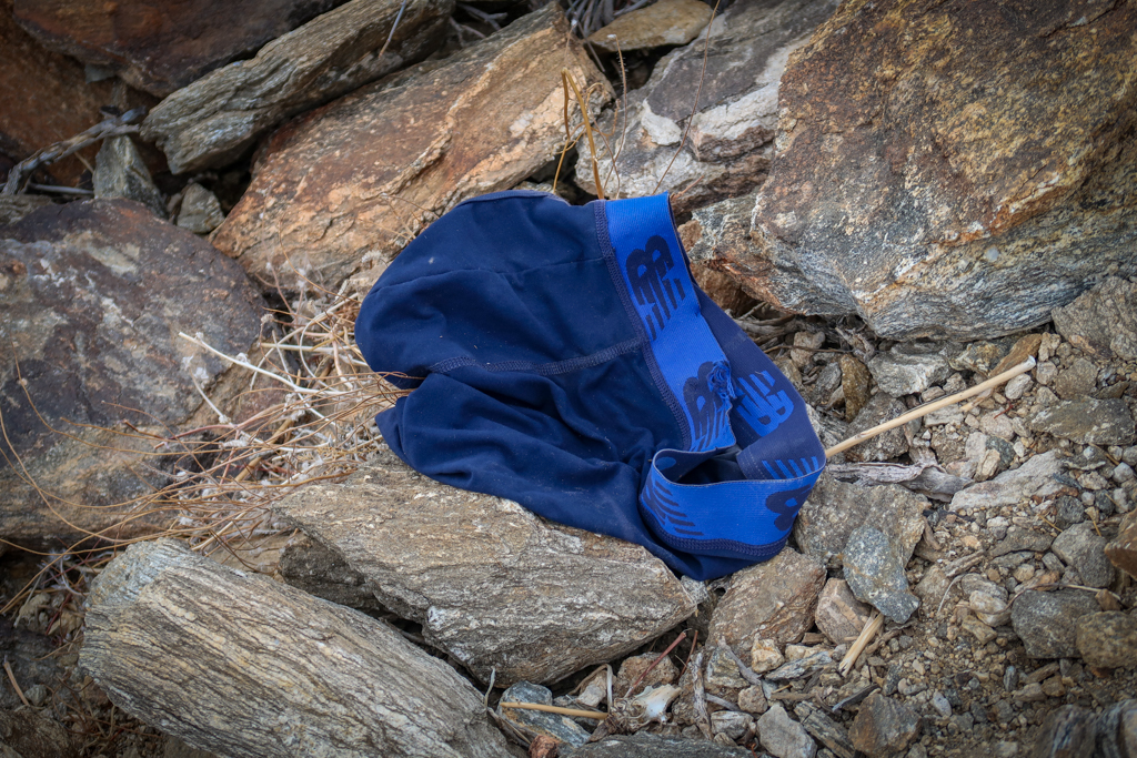 A bright blue pair of mens underpants on the ground next to the trail
