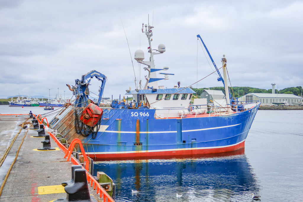 A bright blue fishing boat is docked to the pier at Killybegs