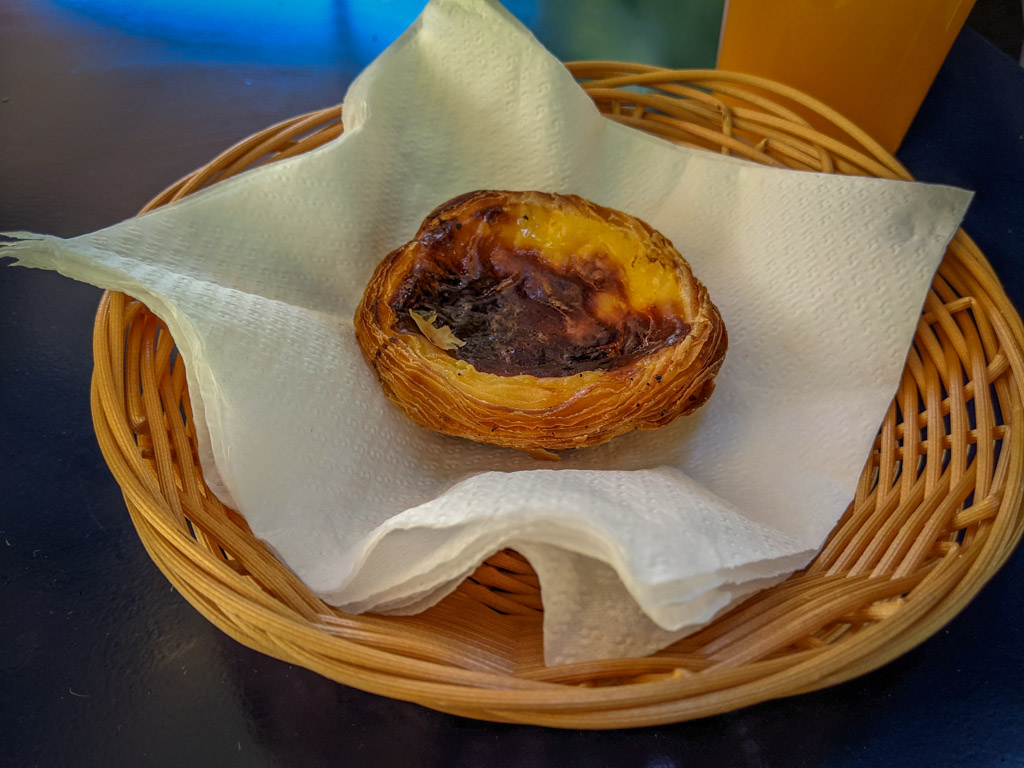 A small custard tart in a flaky pastry shell sits in a display basket