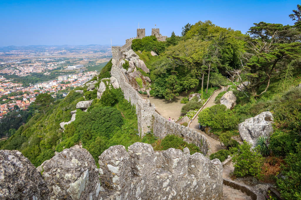 Old stone walls with turrets encircle the top of a hill overlooking Sintra 