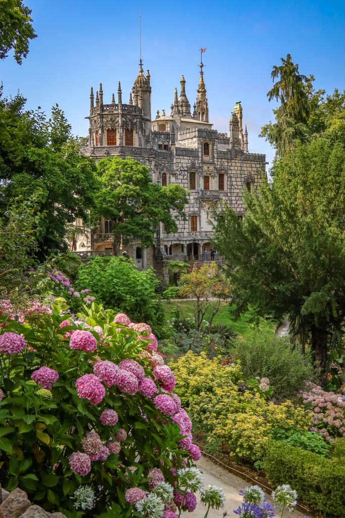 The gothic spires of Quinta da Regaleira stand behind a lovely garden filled with flowers
