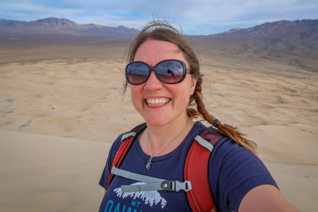 Selfie of the author at the top of the dunes. Her hair is whipping around in the wind and she has no hat.