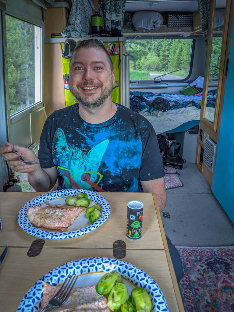 Daniel eats salmon and brussels sprouts inside the RV