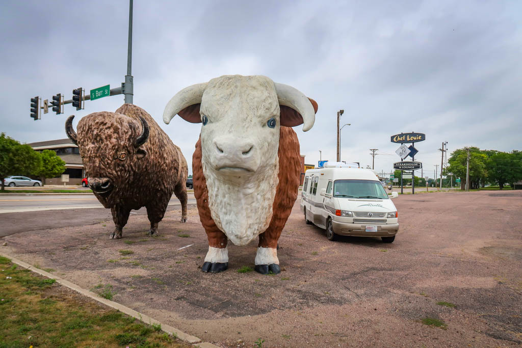 Winnebago Rialta parked next to the Big Steer and Bison Statues. The motorhome is parked next to the statues like it is planning to join them.