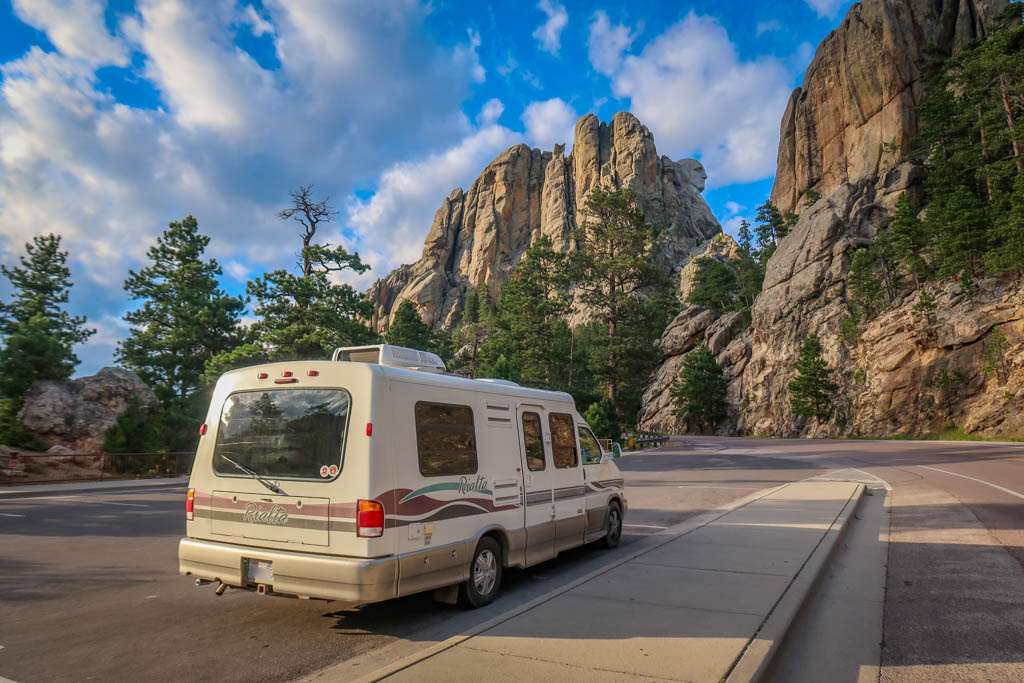 Winnebago Rialta parked in front of Mount Rushmore as viewed from South Dakota Highway 244. Only a portion of Washington's head is visible from this angle. 