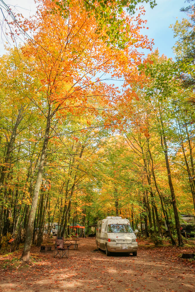 Winnebago Rialta parked under trees with autumn colors of reds, oranges and yellows in Michigan's Upper Peninsula