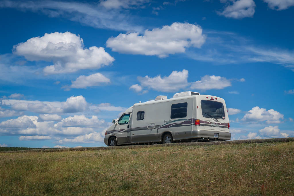 Appa parked under a blue sky with puffy white clouds in Yellowstone National Park