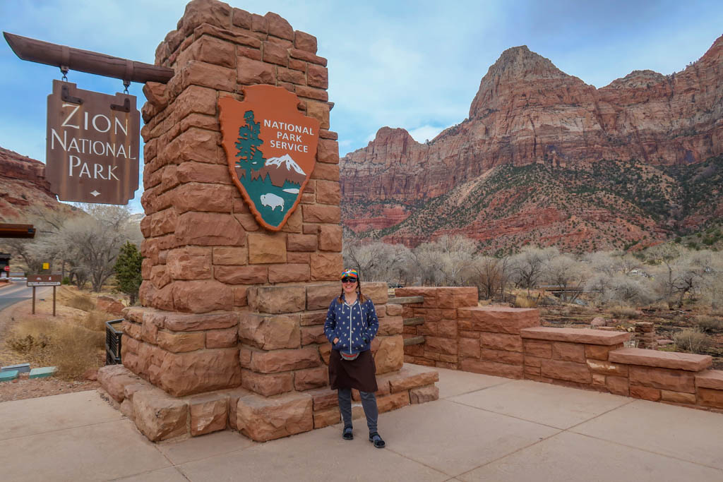 The author stands next to the Zion National Park entrance sign
