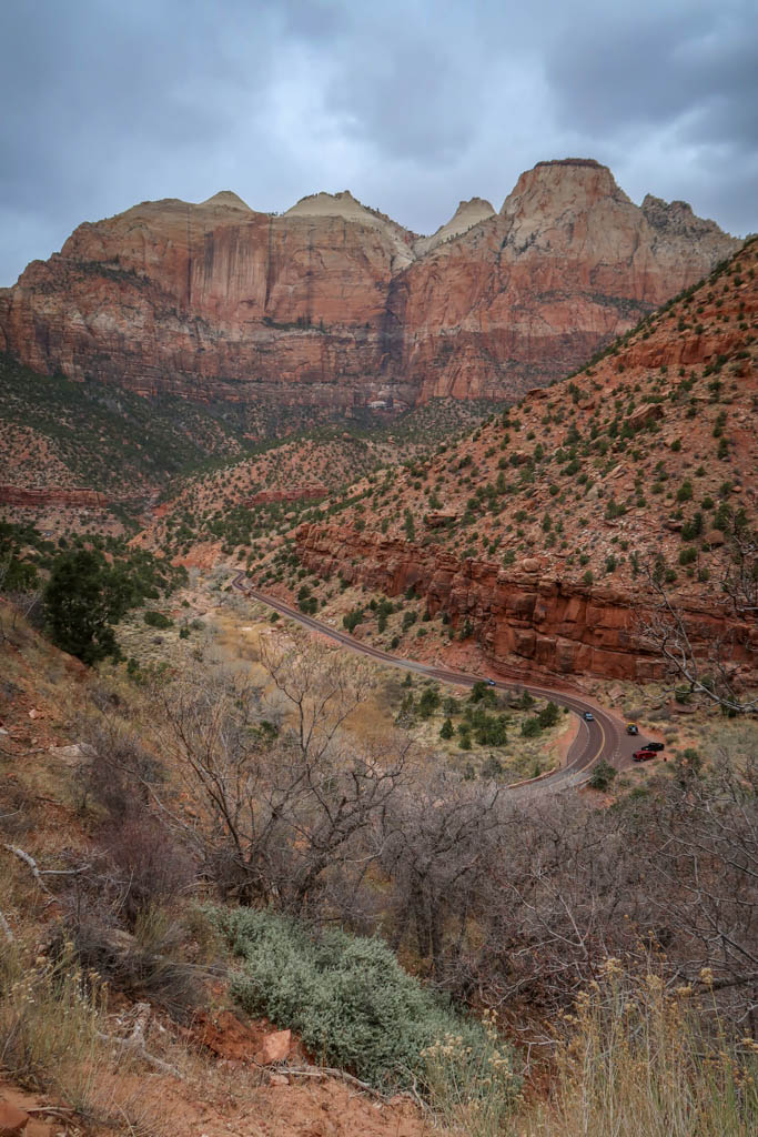 A view of Zion Canyon with the road curving along the valley floor below framed by jagged red cliffs