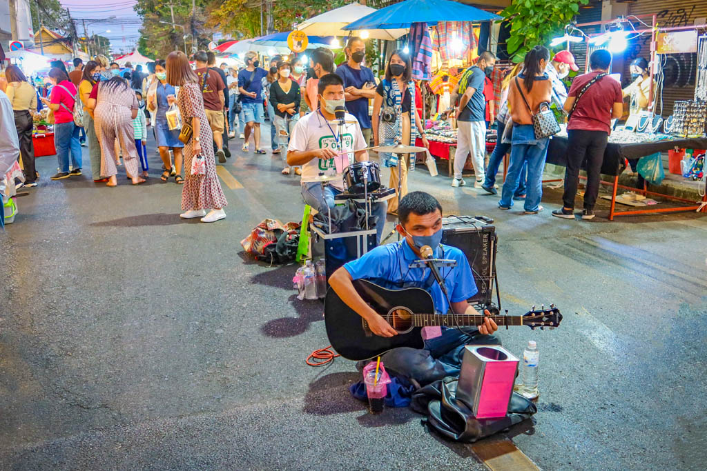 Two blind musicians play music in the middle of the walking street as the crowd stands in the background