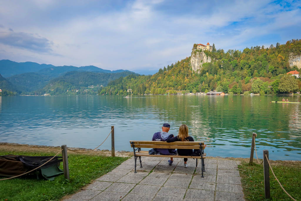 A couple sits on a bench overlooking Lake Bled along the Lake Bled Loop Trail, one of the best Lake Bled hikes.